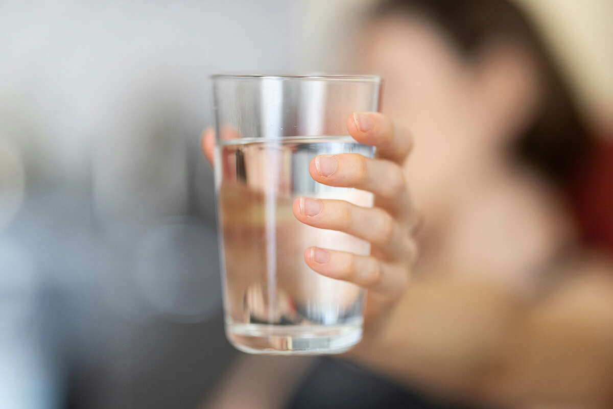 A person holding a clear glass of water